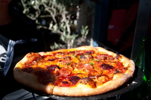 Freshly made Italian Margherita pizza served on a hot plate in a sunny day