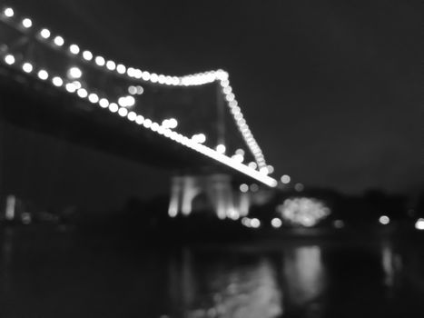 Defocused Iconic Brisbane Story Bridge with city skyscrapers at night in black and white