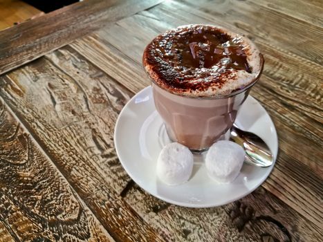 Black and white hot creamy mocca chocolate coffee served on a wooden table with two marshmallow