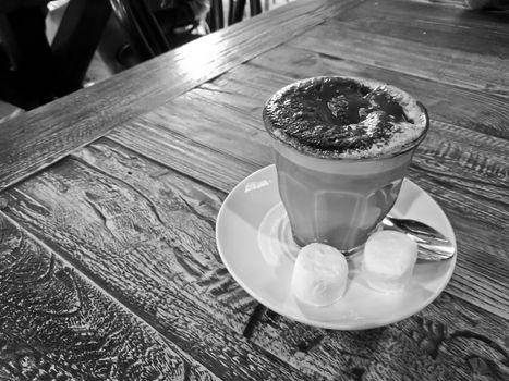 Black and white hot creamy mocca chocolate coffee served on a wooden table with two marshmallow