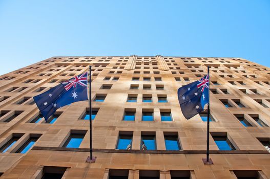 Two Australia flags hanging from a sandstone building