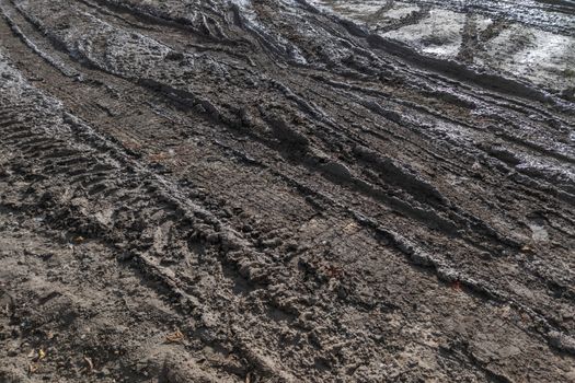 close-up full frame view of wet muddy dirt road at evening sun light.