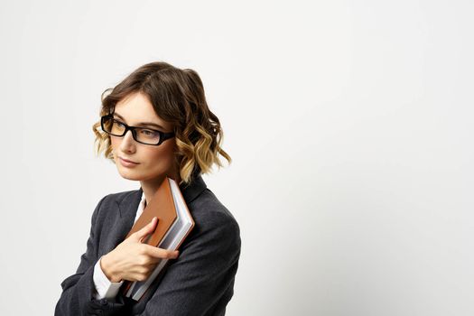 Woman at work with book in hand light background classic suit glasses head. High quality photo
