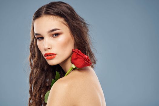 woman with a rose in her hands naked shoulders evening makeup red lips. High quality photo