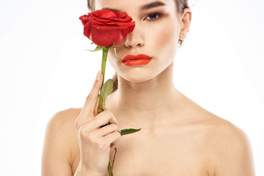 charming brunette girl with makeup on her face and a red rose in her hand. High quality photo