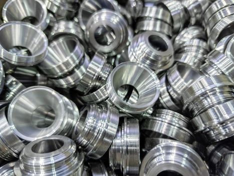 a pile of shiny metal cnc aerospace funnel shape parts production - close-up with selective focus for full frame industrial background