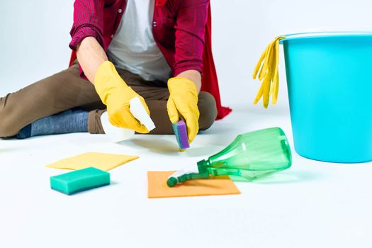 A man in a red raincoat sitting at home washing the floors providing services detergent accessories. High quality photo