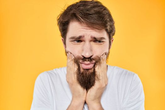 A man in a white t-shirt gestures with his hands studio lifestyle yellow background emotions. High quality photo