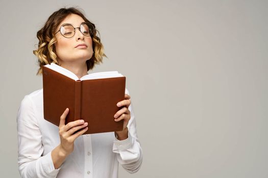 Business woman with notepad and glasses on a light background hairstyle success emotions. High quality photo