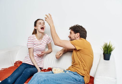 cheerful man and woman on the couch with popcorn and red plaid flower in a pot emotions. High quality photo