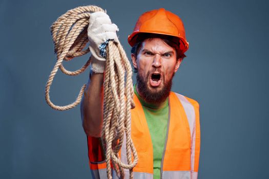 A man in a working uniform with a rope in his hands emotions construction lifestyle. High quality photo