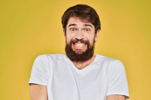 Bearded man in white t-shirt emotions close-up fun yellow background. High quality photo