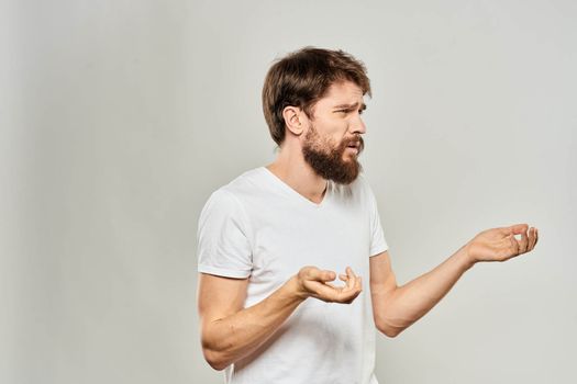 man in white t-shirt gesturing with his hands studio dissatisfaction lifestyle light background. High quality photo