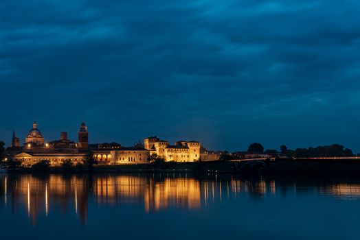 Panorama of the city of Mantua illuminated and reflected in the lake water, night cityscape