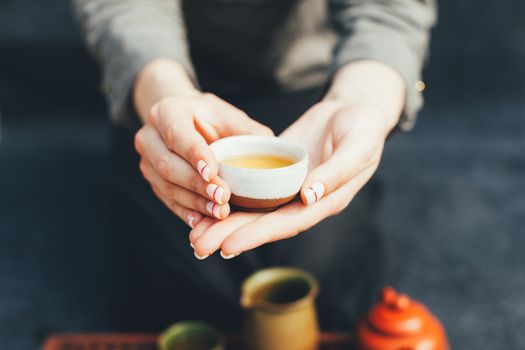 Woman offers hot tea in a vintage ceramic cup. Traditional tea ceremony