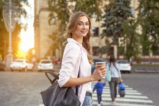 Businesswoman standing summer day city street pedestrian crosswalk near corporate building Business person Outdoors Successful european caucasian woman freelancer with coffee paper cap in hands