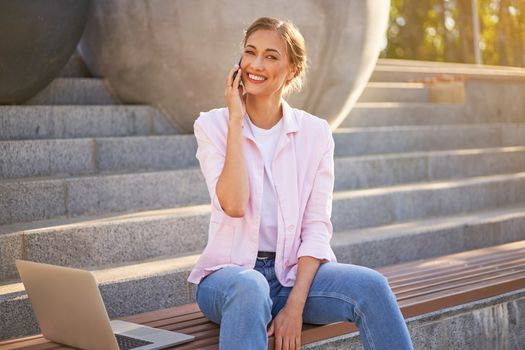 Businesswoman sitting stairs summer park using laptop and smartphone Business persone working remote. Outdoor. Successful Young european caucasian woman freelancer meeting online