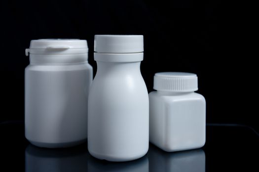 White medicine bottle on black background, medical concept