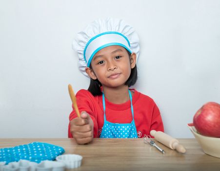 Cute girl in chef uniform and simulated cooking toys in the kitchen counter.