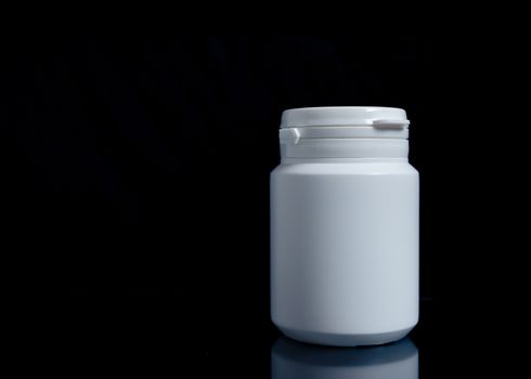 White medicine bottle on black background, medical concept