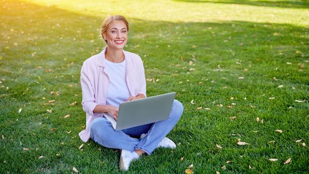 Businesswoman sitting grass summer park using laptop Business persone working remote. Outdoors Successful european caucasian woman freelancer make video call teacher study work online lessons