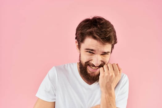 Man in white t-shirt gestures with hands emotions lifestyle cropped view pink background. High quality photo