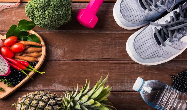 Top view of various fresh organic fruit and vegetable in heart plate and sports shoes, dumbbell and water, studio shot on wooden gym table, Healthy diet vegetarian food concept, World food day