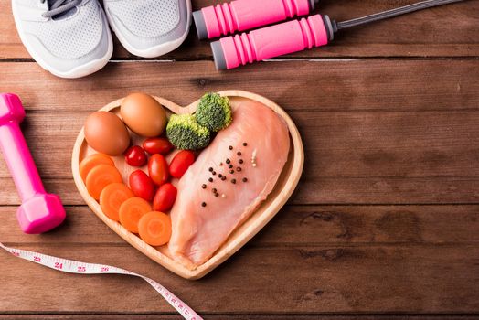 Top view of Raw chicken breasts fillets no boneless with spices in heart plate wood and sport or athlete's equipment dumbbell
running shoes on wooden background, Healthy lifestyle diet food concept