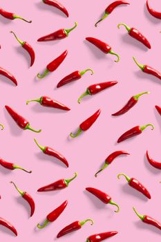Creative background made of red chili or chilli on pink backdrop. Minimal food backgroud. Red hot chilli peppers background, not pattern