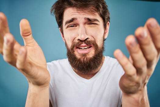 Man in white t-shirt lifestyle studio emotions facial expression blue isolated background. High quality photo