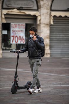 terni,italy october 26 2020:boy with medical mask causes covid 19 and carries the scooter