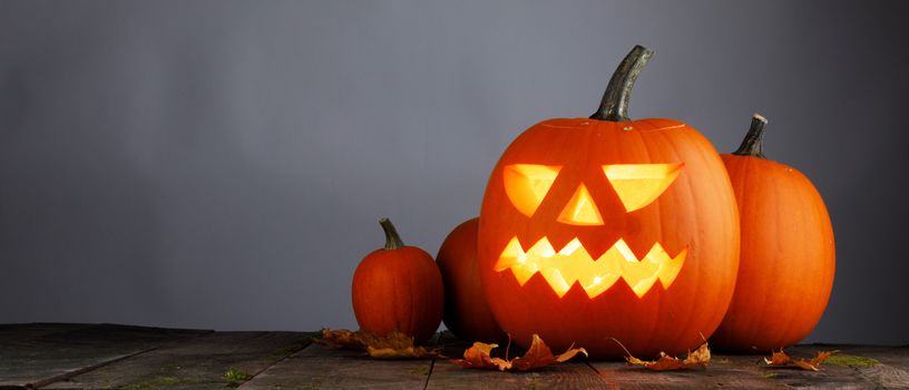 Halloween pumpkin head jack o lantern and candles on gray background