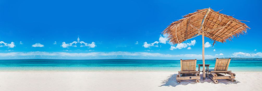 Beach chairs and umbrella on a beautiful tropical sea beach, view with copy space