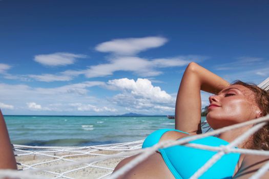 Girl in bikini relaxing in hammock on the beautiful paradise beach