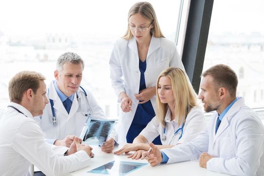 Team of experts doctors examining lungs X-ray report on hospital office meeting