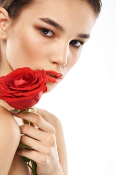 Beautiful woman with red rose near face makeup naked shoulders portrait. High quality photo