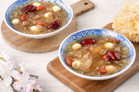 Close up of traditional Chinese sweet snow white fungus soup with lotus seed, red dates (jujube) and wolfberry (goji berry, gojiberry) on white background.
