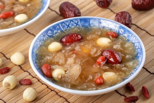 Close up of traditional Chinese sweet snow white fungus soup with lotus seed, red dates (jujube) and wolfberry (goji berry, gojiberry) on white background.