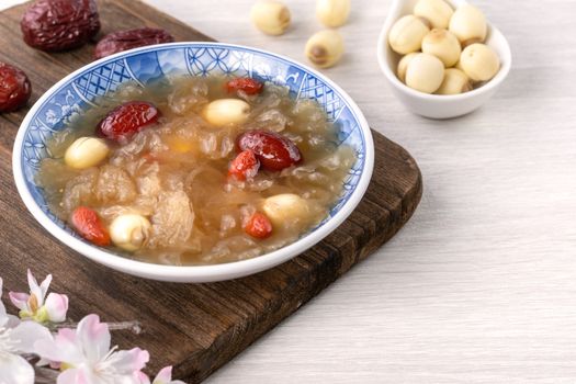 Close up of traditional Chinese sweet snow white fungus soup with lotus seed, red dates (jujube) and wolfberry (goji berry, gojiberry) on white background.
