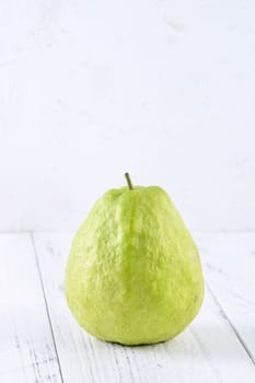 Delicious beautiful guava set with fresh leaves isolated on bright white wooden table background, close up.