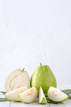 Delicious beautiful guava set with fresh leaves isolated on bright white wooden table background, close up.