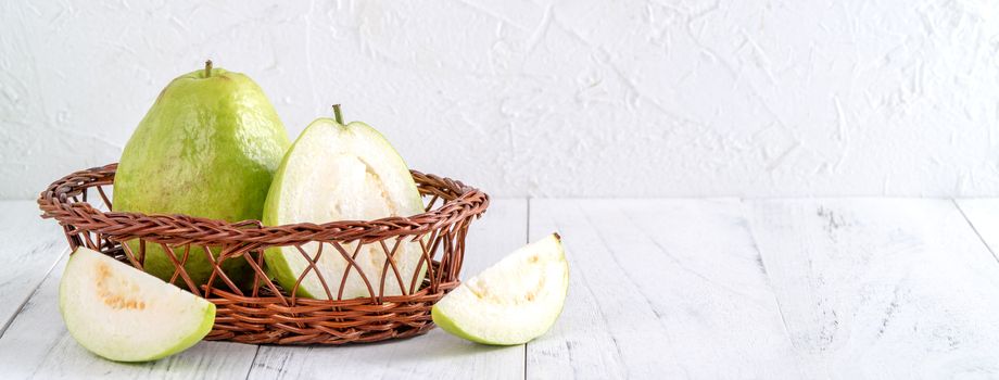 Delicious beautiful guava set with fresh leaves isolated on bright white wooden table background, close up.