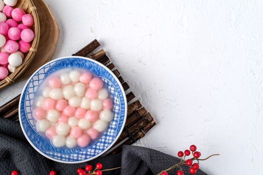 Top view of red and white tangyuan (tang yuan, glutinous rice dumpling balls) in blue bowl on white background for Winter solstice festival food.