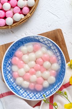 Top view of red and white tangyuan (tang yuan, glutinous rice dumpling balls) in blue bowl on white background for Winter solstice festival food.