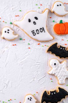 Top view of Halloween festive decorated icing gingerbread sugar cookies on white background with copy space and flat lay layout.