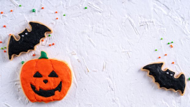 Top view of Halloween festive decorated icing gingerbread sugar cookies on white background with copy space and flat lay layout.
