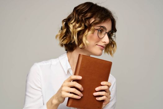 woman with notepad in hands business work beige background glasses hairstyle. High quality photo