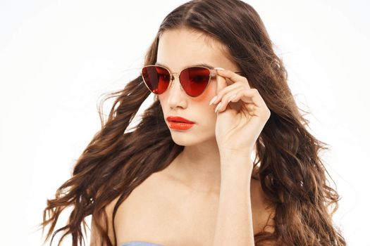 Portrait of brunette woman in sunglasses naked shoulders light background. High quality photo