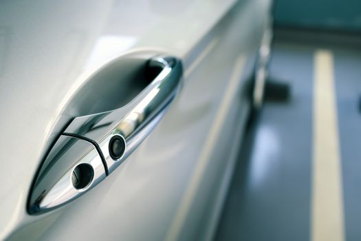 door handle of modern car parked at parking lot of condominium, push button to lock vehicle, keyless entry door handle, selective focus