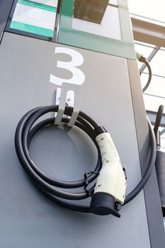 power supply connecter to plug-in electric vehicle or electric car at charging station in car park area of shopping plaza. charging technology for future automotive and city life.